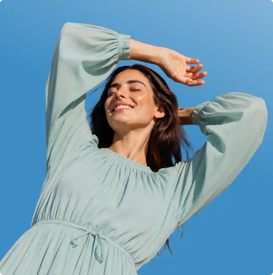Woman in a pale blue dress smiling in the sun
